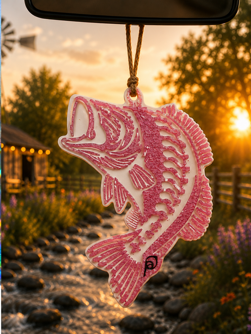 Pink glitter bass fish car freshie hanging from rearview mirror at golden sunset