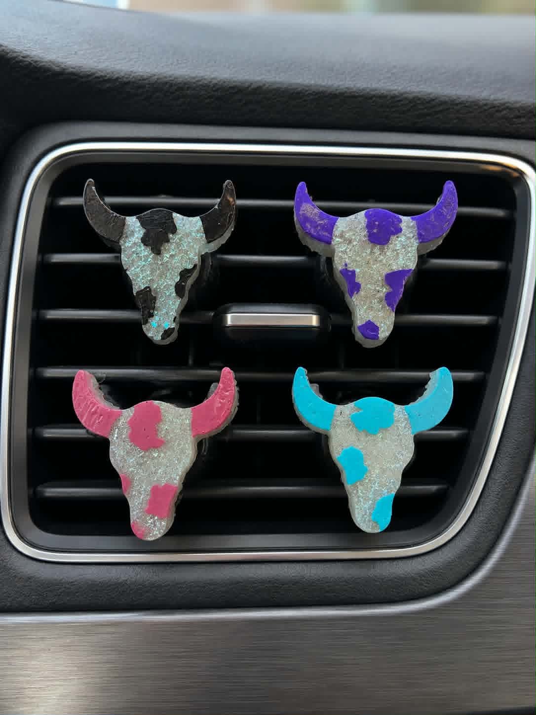 Hollow Creek Longhorn vent clips in black, purple, pink, and teal on a car vent